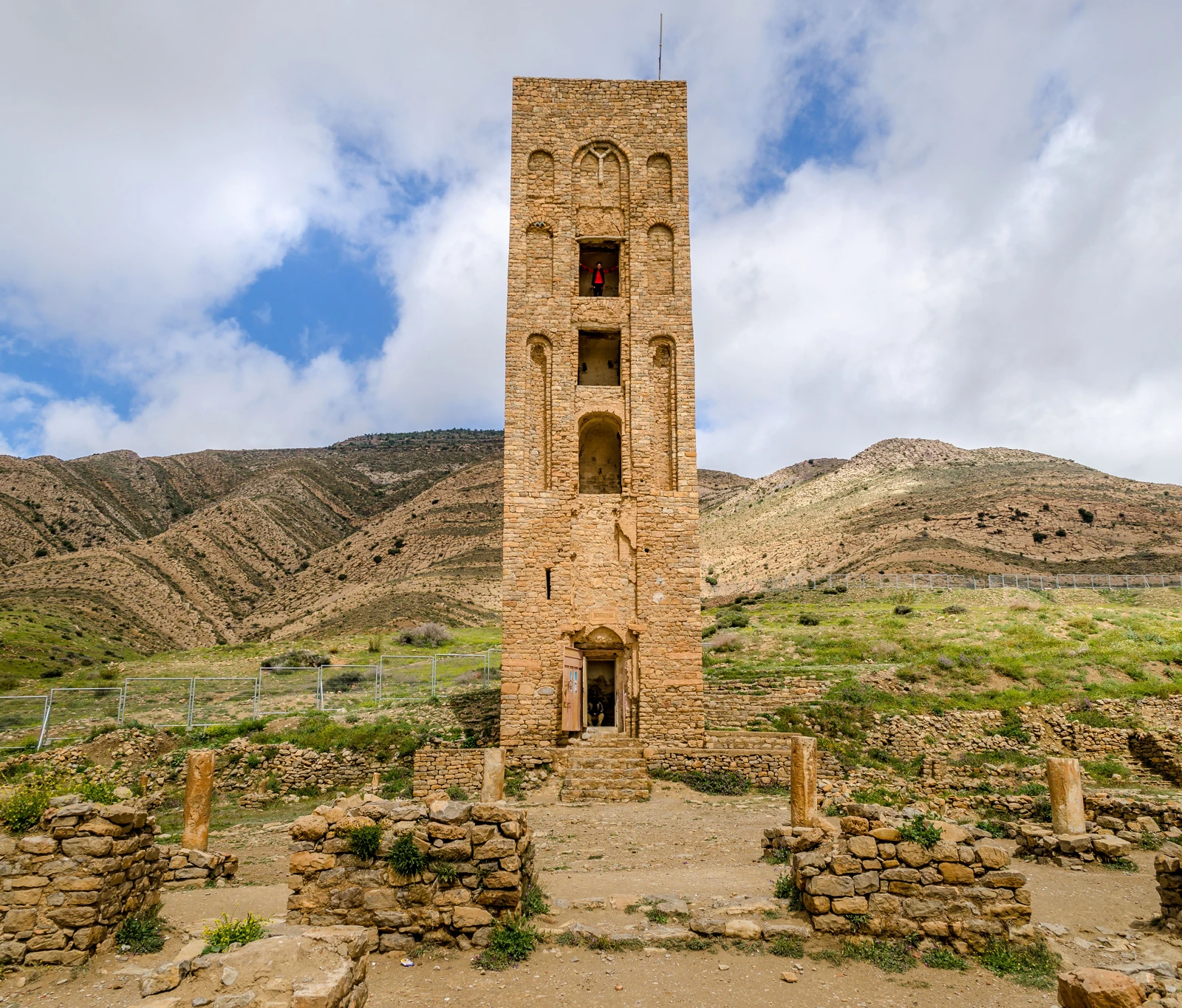 Minaret de la Kalâa des Béni Hammad parmi les vestiges de pierre, devant les collines