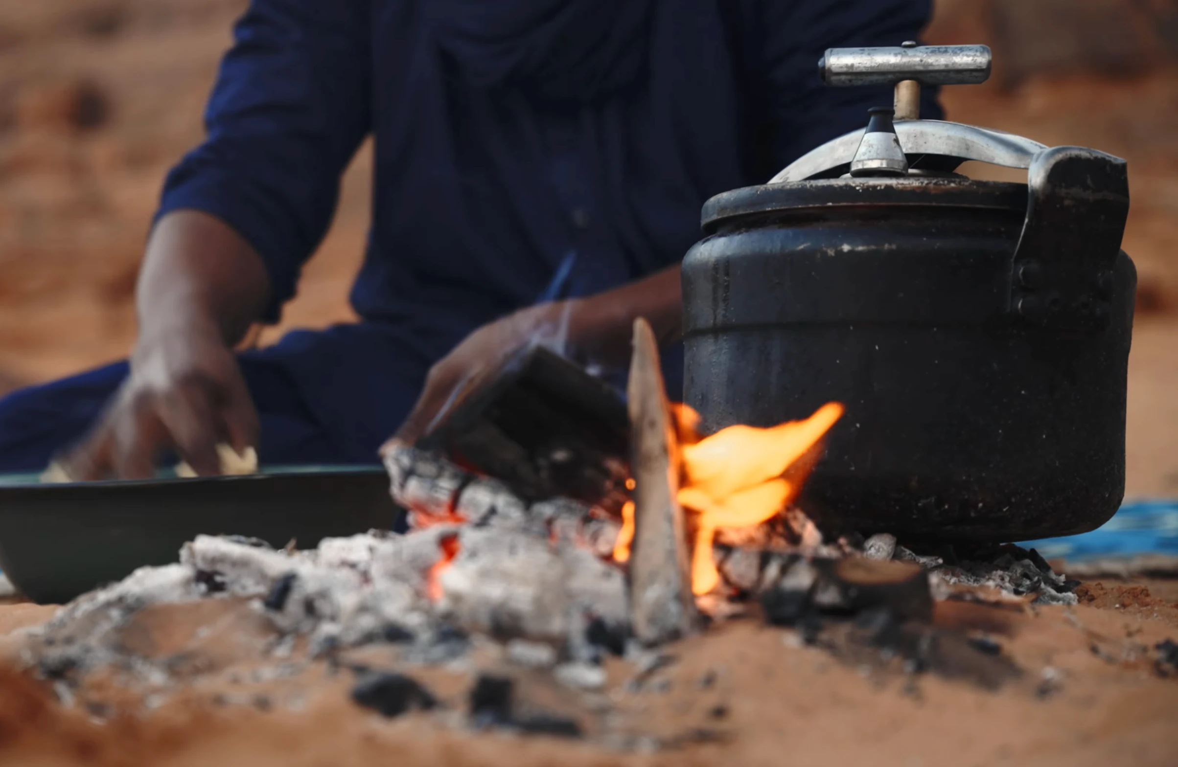 Préparation de la taguella autour d’un feu dans le Sahara