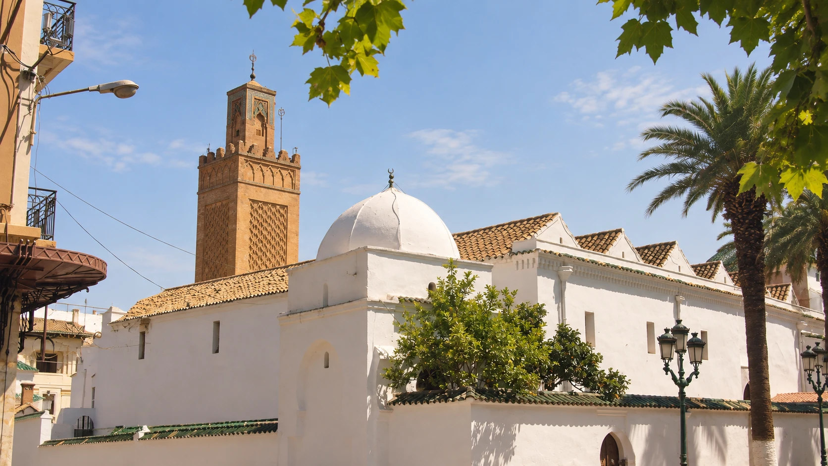 Illustration assistée par IA : Le minaret ocre et la coupole blanche de la Grande Mosquée de Tlemcen, entre feuillages et palmiers.