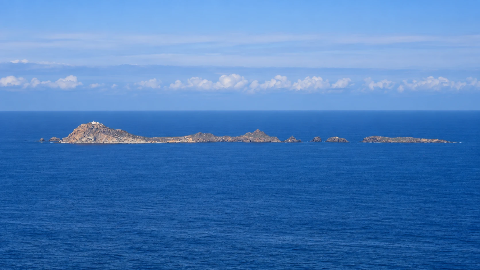 Illustration assistée par IA : La silhouette rocheuse des îles Habibas et leur phare, au large d’Oran, en pleine Méditerranée.