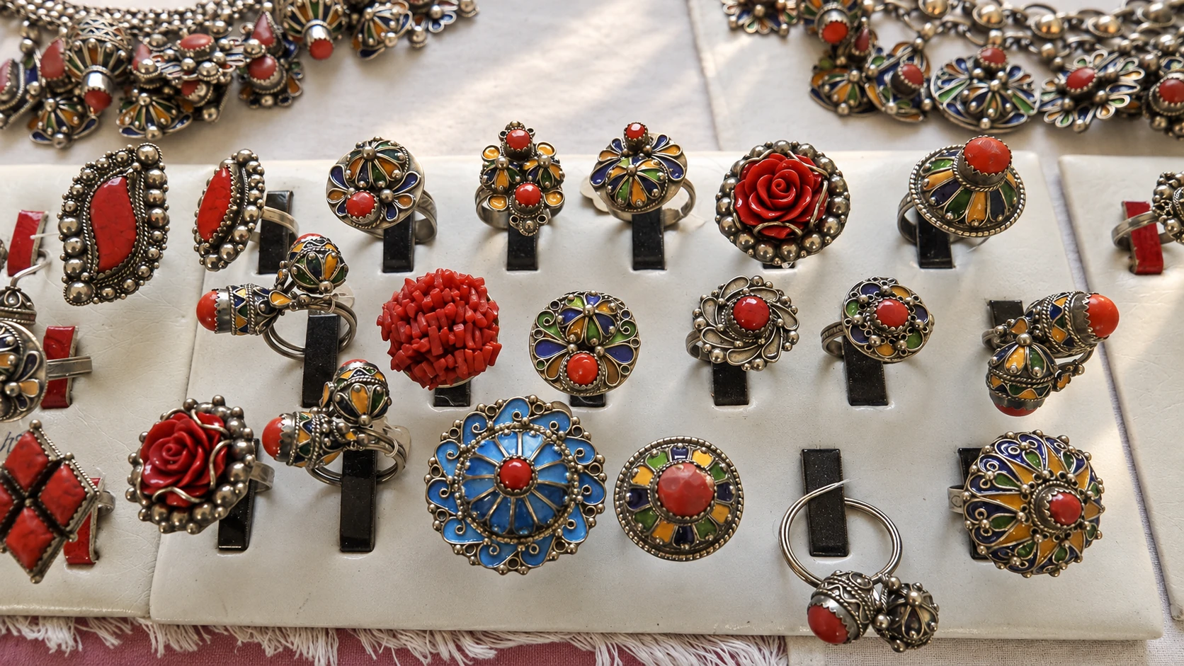Illustration assistée par IA : Bijoux finis émaillés d’Ath Yenni présentés sur un étal.