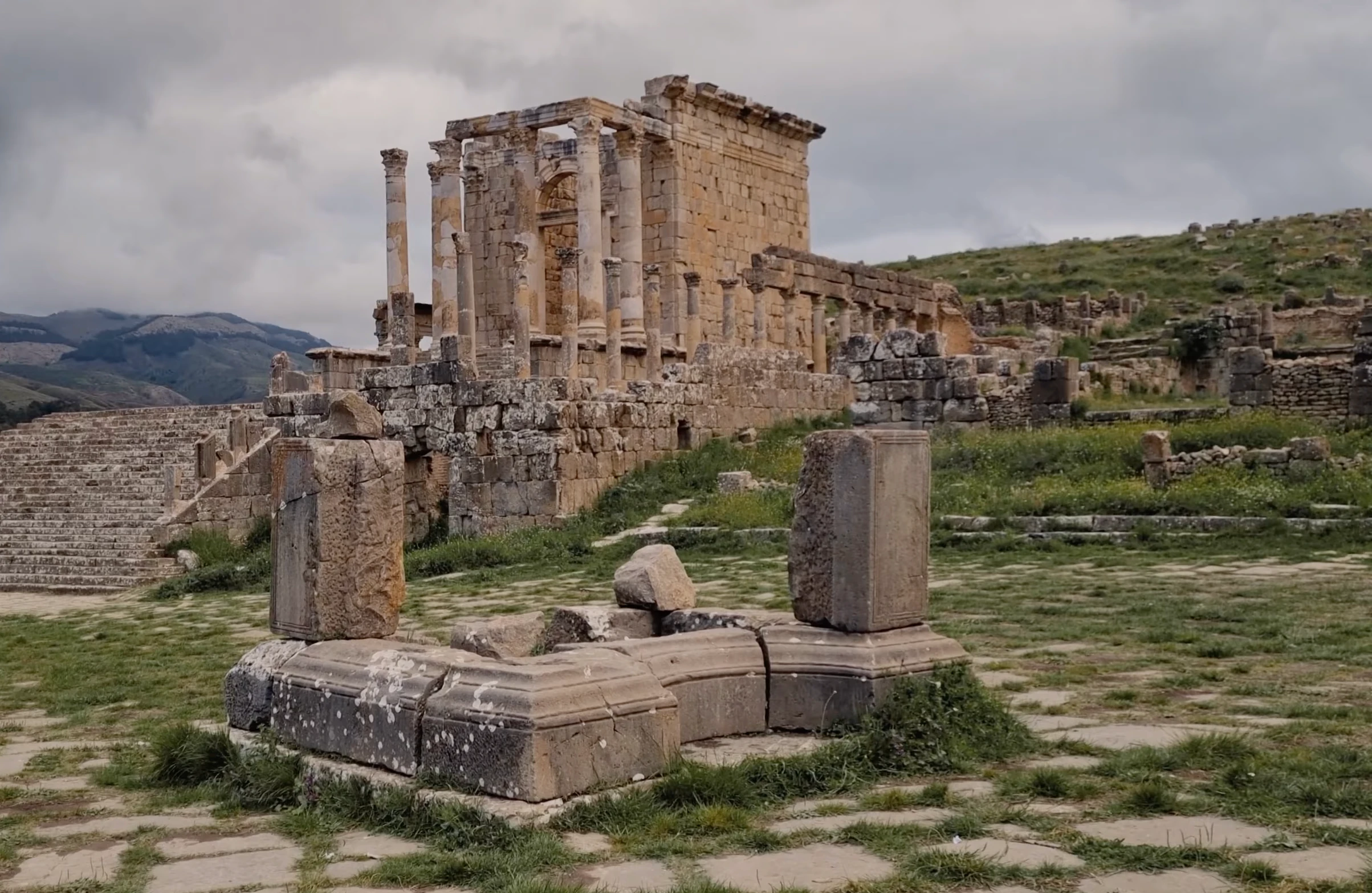 Le temple septimien et les vestiges du forum de Djemila, sur une pente herbeuse