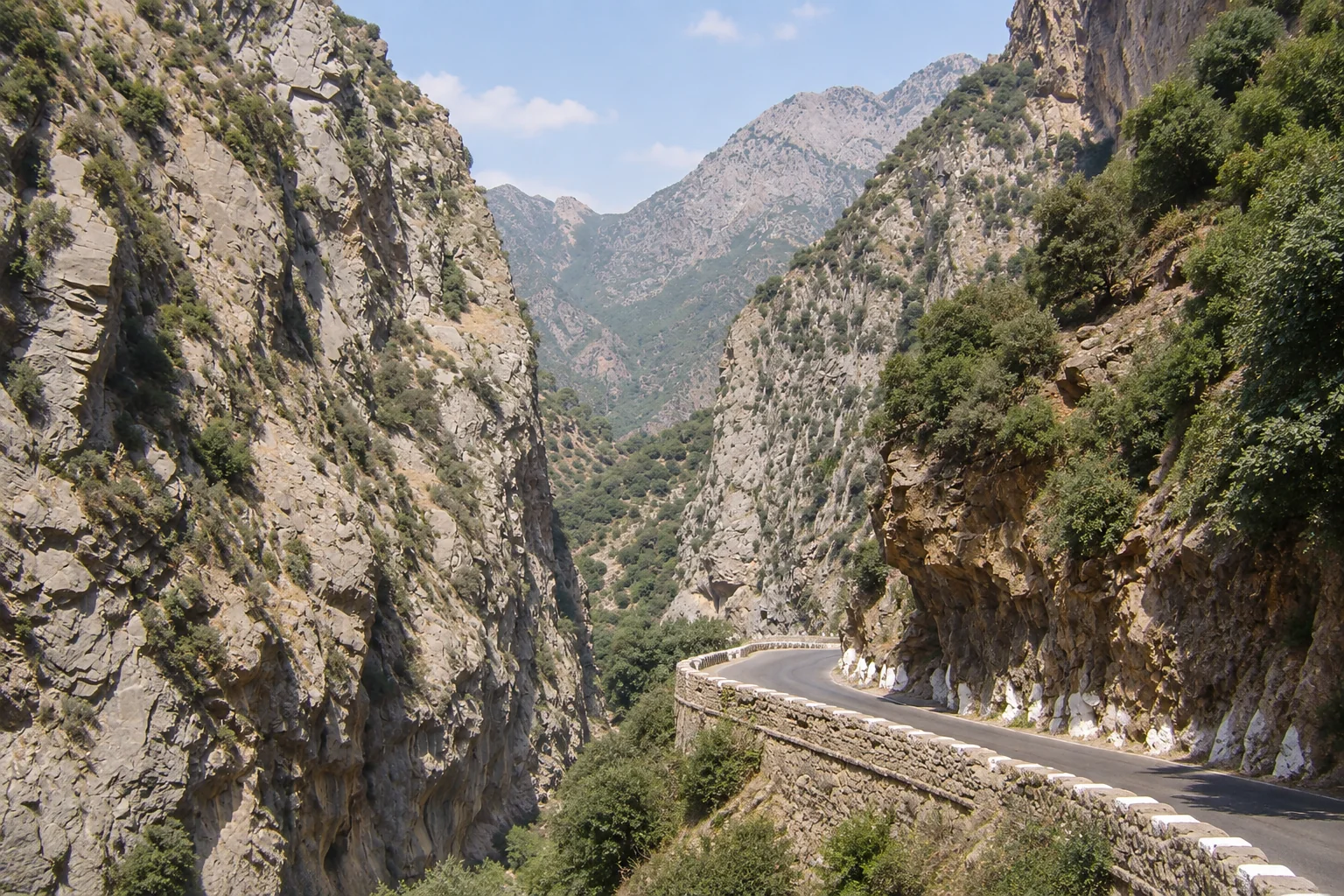 Une route courbe au pied des hautes parois des gorges de Kherrata.