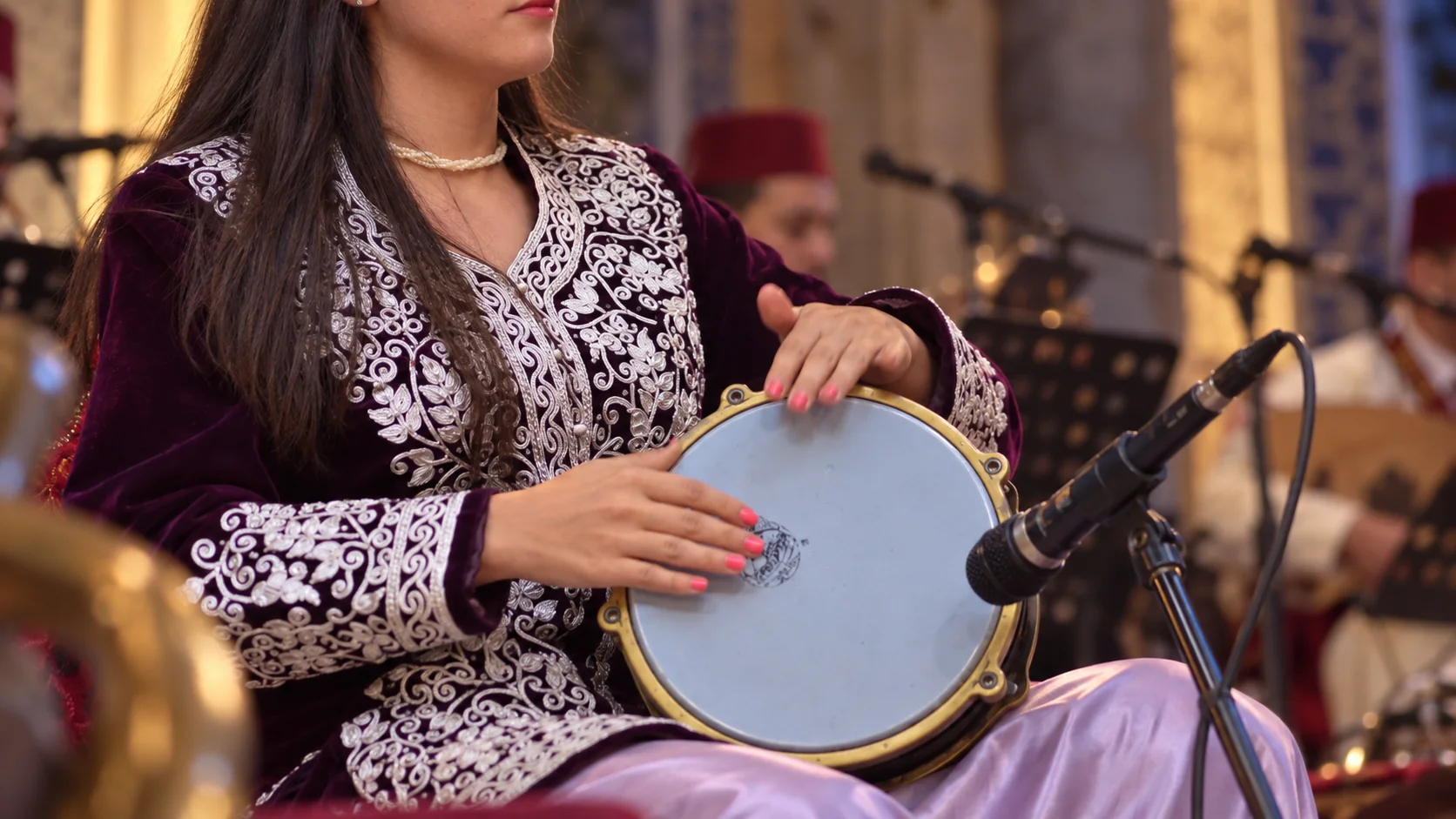 Illustration assistée par IA : Vue d’une musicienne jouant une percussion lors d’une soirée musicale à Constantine.