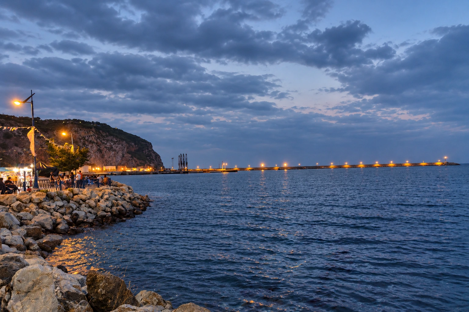 La promenade de la Brise de Mer et la jetée éclairée à Béjaïa, à la tombée du jour.