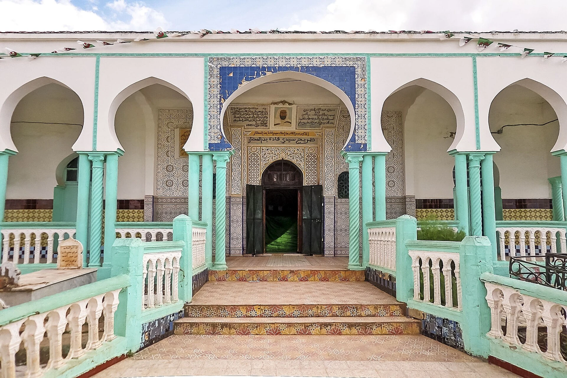 Façade du mausolée de Sidi Kada Ben El Mokhtar, arcades, colonnes turquoise et inscriptions conservées dans la photo réelle de 2016.