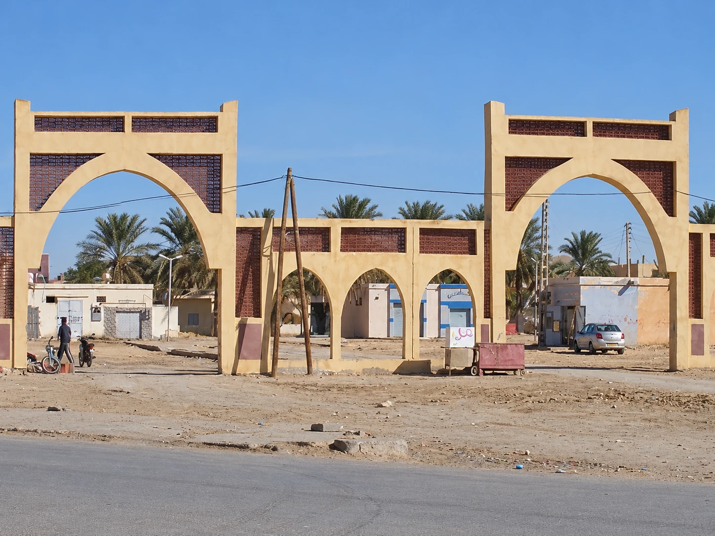 Portail urbain de Temacine, deux grandes arches et palmiers à l’arrière-plan.