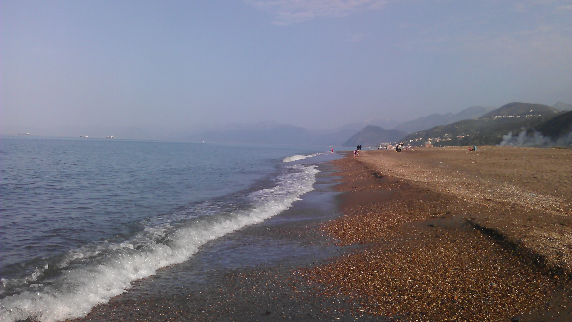 Vagues sur la plage de Tichy, devant les montagnes du littoral de Béjaïa