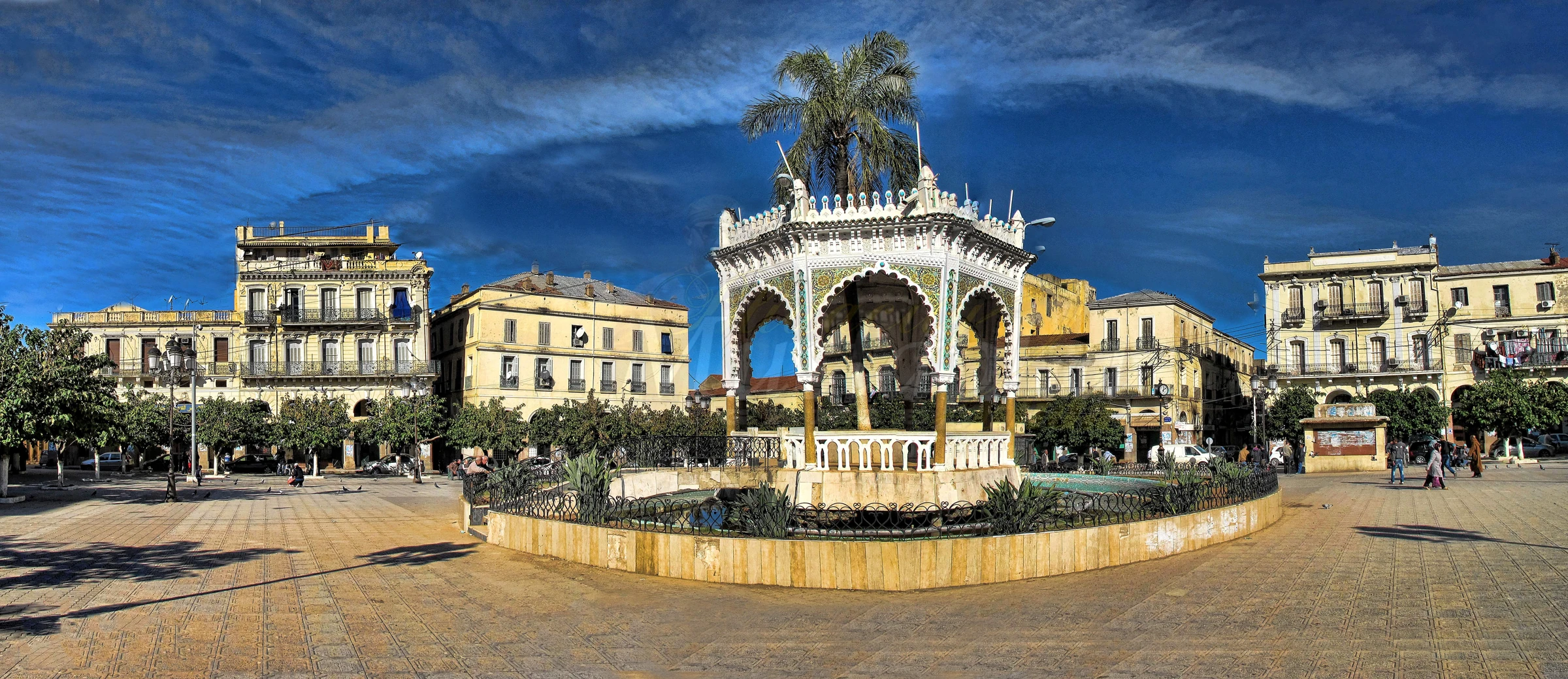 Kiosque et palmier de la place du 1er Novembre à Blida, entourés de façades historiques