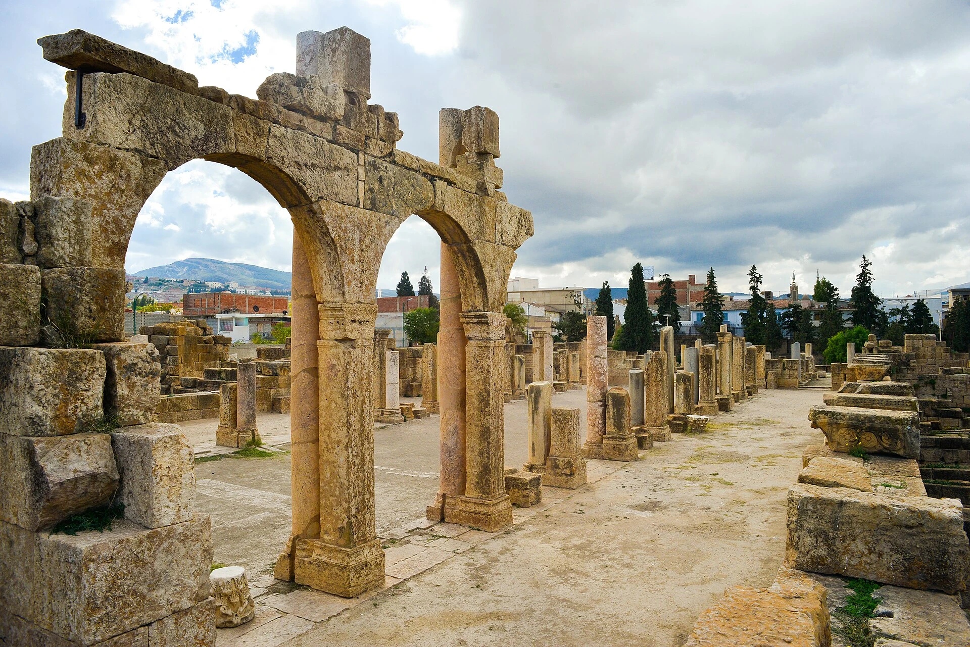 Ruines de la basilique de Tébessa, arcades et colonnes ; photographie réelle conservée sans redessiner les éléments archéologiques.