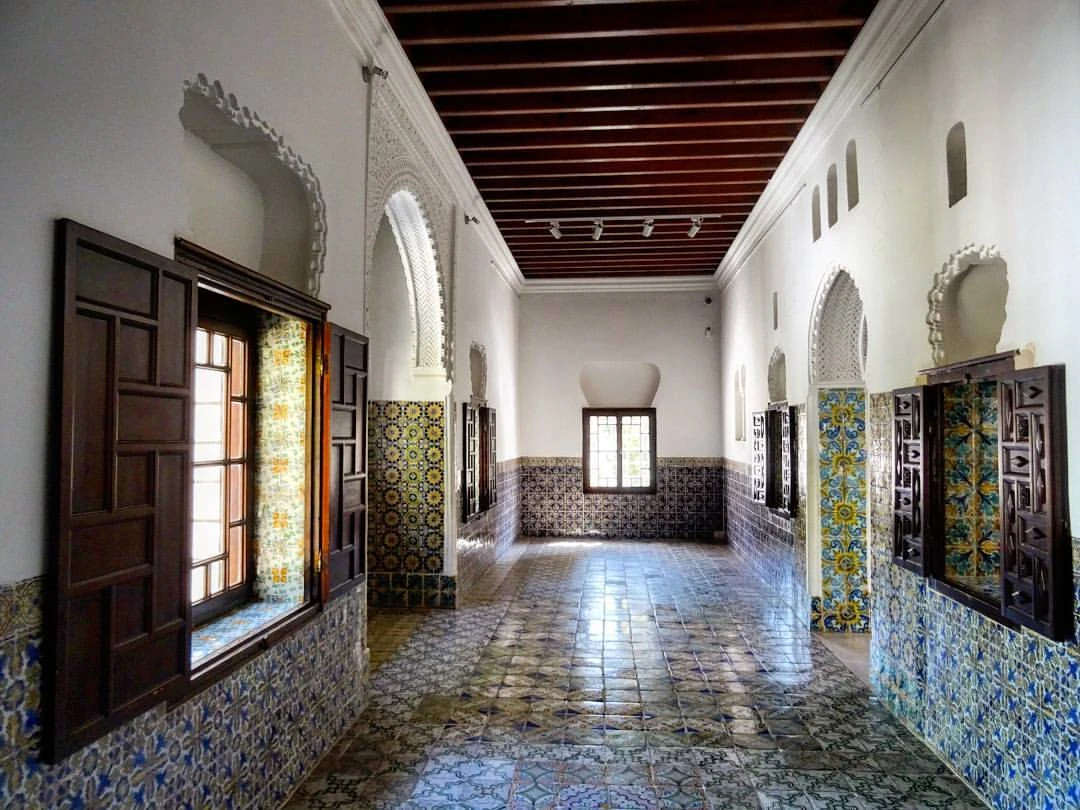 Salle du musée du Bardo à Alger, aux boiseries sombres et murs décorés de faïences colorées.