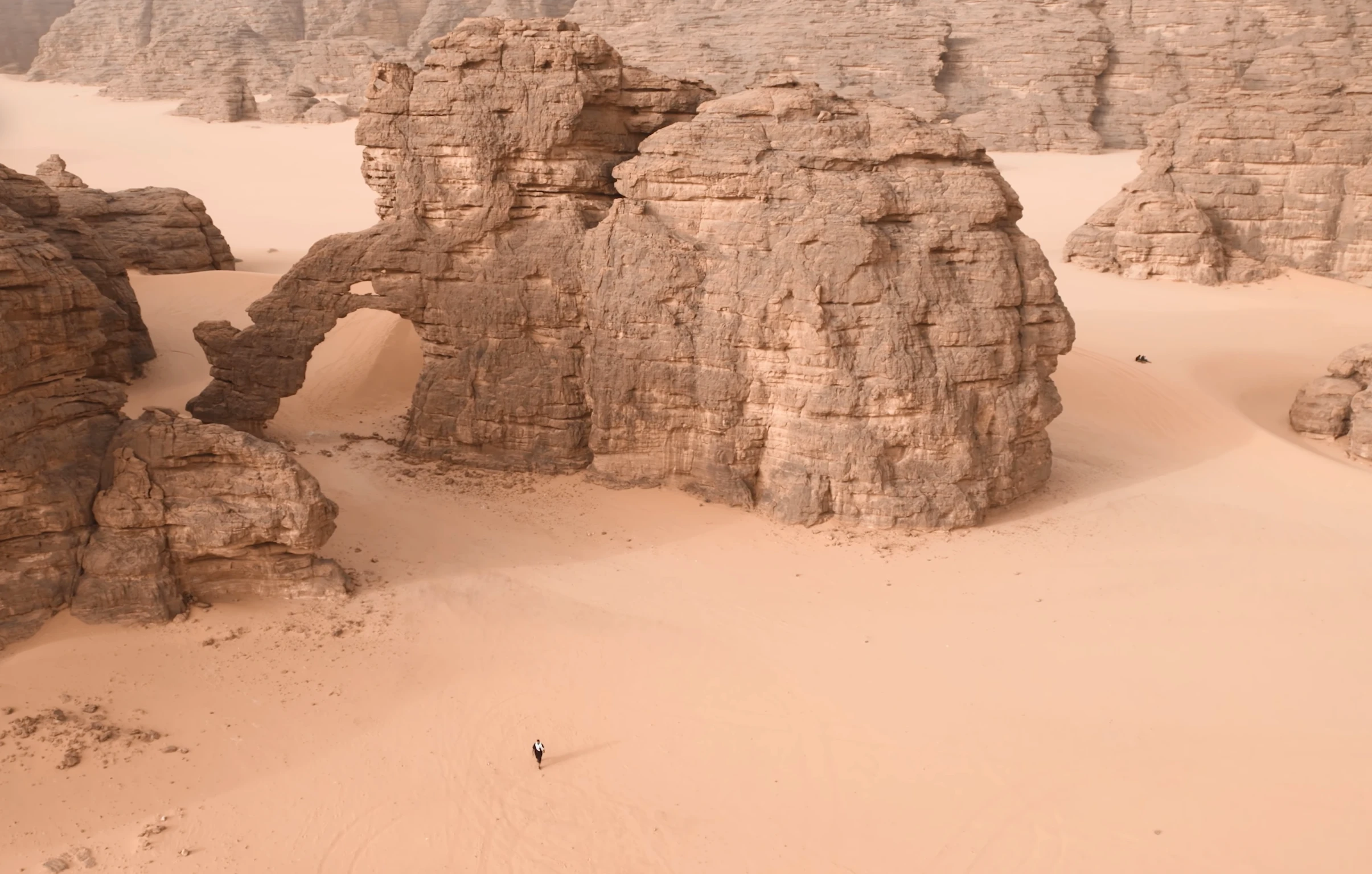Arche et reliefs de grès dans le Tassili n’Ajjer, avec un marcheur sur le sable
