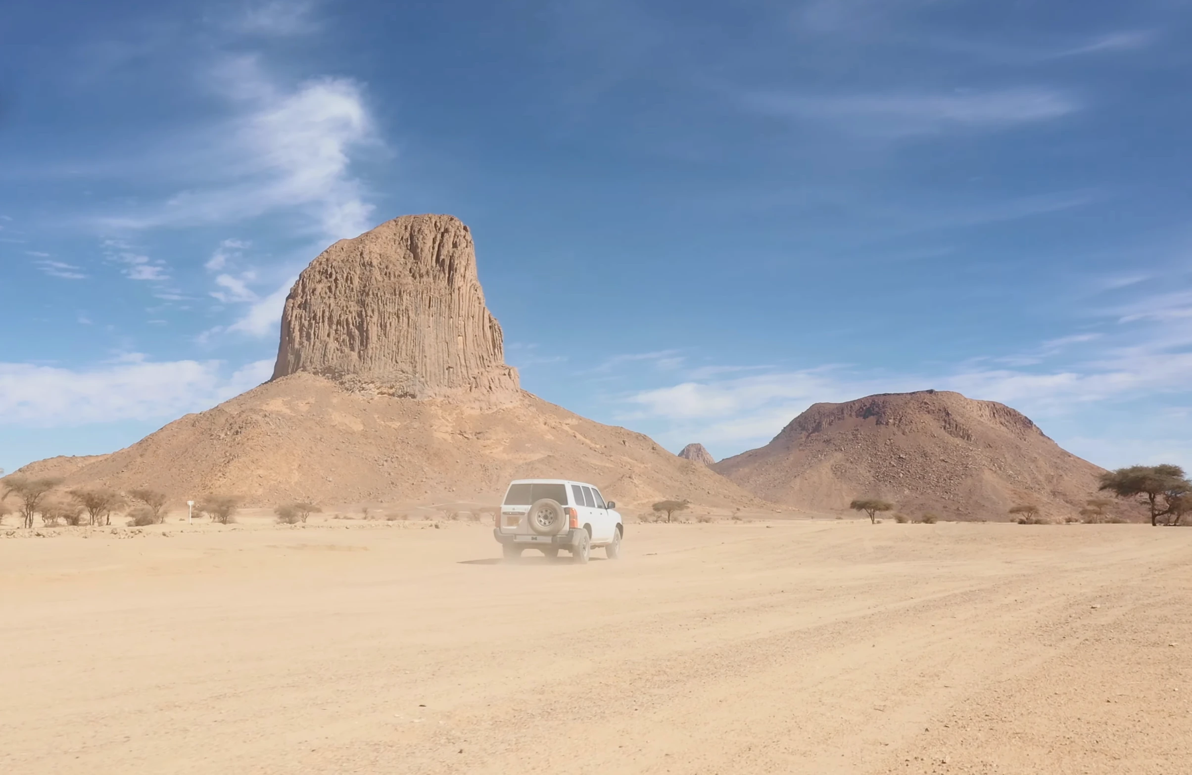 Véhicule tout-terrain sur une piste au pied des reliefs volcaniques du Hoggar